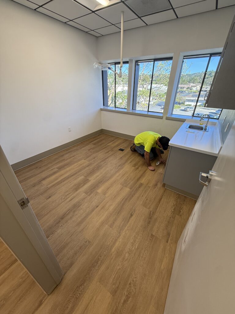 RC Floors installer laying luxury vinyl plank in a bright living room
